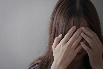 頭を抱える、辛そうな若い女性