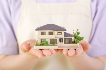 住宅の模型を持つエプロン姿の若い女性