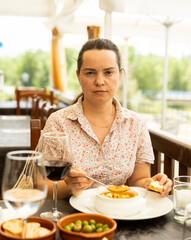 Portrait of woman spending time on open terrace of restaurant and eating traditional spanish...