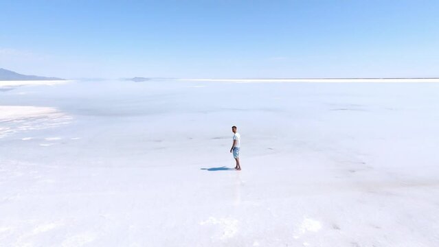 Young man exploring Salt Lakes. Lonely man standing in the desert field. Aerial view. Travel alone.