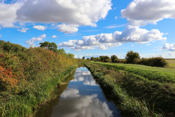 Fototapeta na wymiar landscape with river and blue sky, cloud reflection in the water, early autumn in the countryside