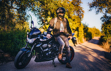 Fototapeta na wymiar motorcyclist leaning on his motorbike waiting for his friends