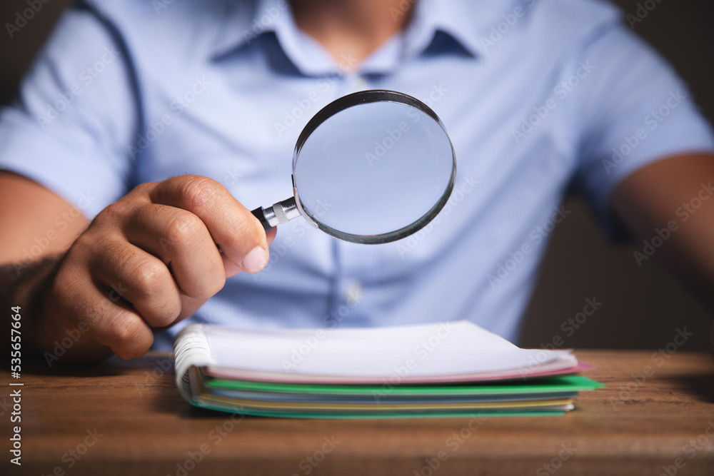 Poster Man looks at papers with a magnifying glass