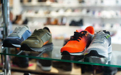 New various sportive footwear on shelves in shoe shop.