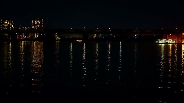 A ferry goes to dock at a wharf on the river at night.