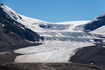 Athabasca glacier with people silhouettes walking and the columbia icefield explorer vehicles, Jasper national park, Alberta, Canada.