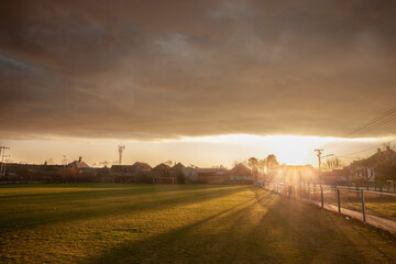 Panorama of a sunset over a rural european football field (a soccer playground), in a small...