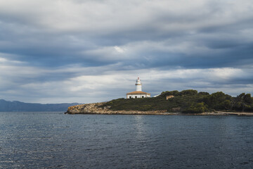 Fototapeta na wymiar Alcanada Lighthouse (Faro de Alcanada) was built in 1861 and is located on a small island 5 km from Alcudia, Mallorca, Spain.