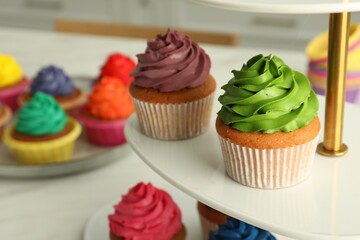 Delicious cupcakes with colorful cream on stand, closeup