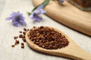 Wooden spoon of chicory granules on sackcloth, closeup