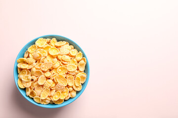 Bowl of tasty crispy corn flakes on light background, top view. Space for text