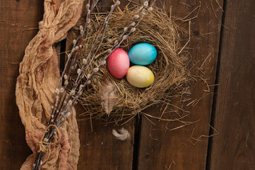 Painted Easter chicken eggs in a nest and willow branches. Holiday Easter concept background. High quality photo