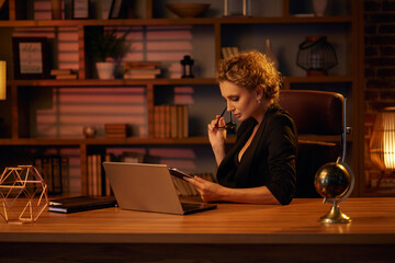 Purposeful young business woman, professional entrepreneur, works behind a laptop. Businesswoman, in a beautiful office in cinematic light. Finance, startups, stock trading, online work