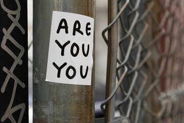 Graffiti sticker on a fence that reads "Are You You" © Jenna
