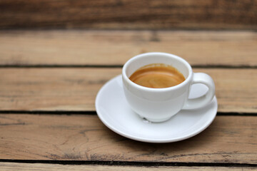 Espresso coffee in white ceramic cup on wooden table background.  Espresso can be made with a wide variety of coffee beans and roast degrees.