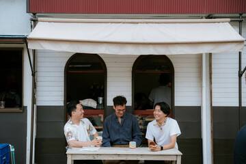 テラスで談笑する三人のアジア人男性