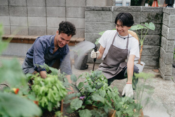 ホースで植物に水をあげる男性と手伝うパートナー