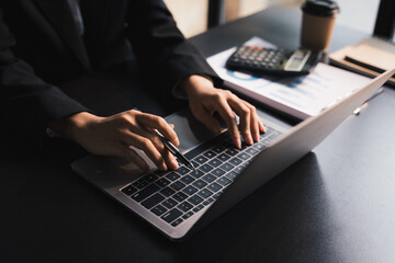 Close-up businessperson typing and searching data internet on laptop, graph diagram,  and...
