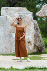 happy pregnant woman standing in park