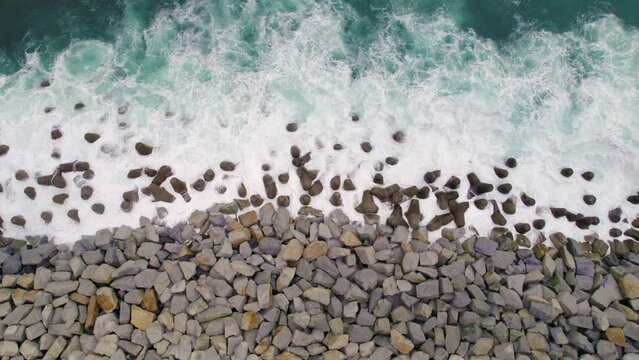 vista a&eacute;rea cenital desde dron del mar color turquesa. Se ven olas con espuma blanca y rocas de la orilla del mar