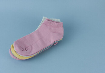 A stack of colorful socks on a blue background. Colored socks close-up.