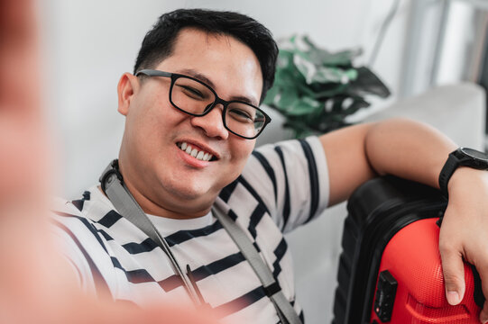 Happy Asian traveler man glasses selfie on smartphone with luggage