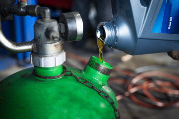 Auto mechanic pouring gear oil into the oil tank.  