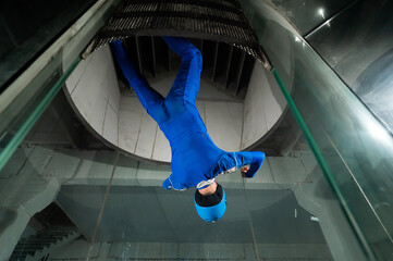 A man in overalls and a protective helmet enjoys flying in a wind tunnel. Free fall simulator
