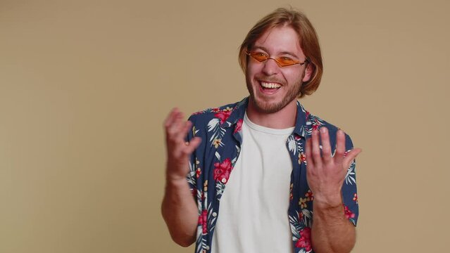 Little bit crazy. Blonde joyful sincere man demonstrating tongue out, fooling around, making silly faces, madness, making playful silly facial expressions and grimacing. Young guy on beige background