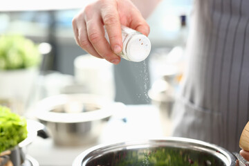 Chef salting boiling water or foods in saucepan