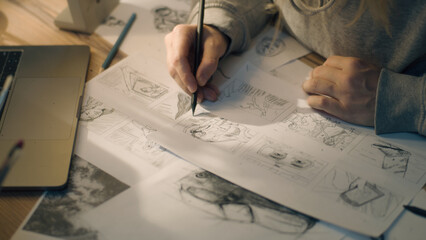 Closeup hands of a woman making pencil sketches. Working on a storyboard in a home based design...