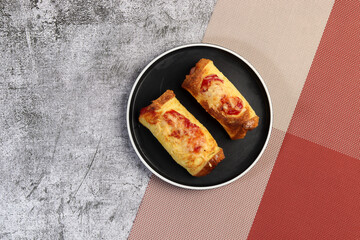 Toasted hot dog wraps on a  round plate on a dark gray background. Top view, flat lay