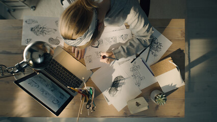 Young woman working on a storyboard in a design studio. A laptop and stationary jar on the table....