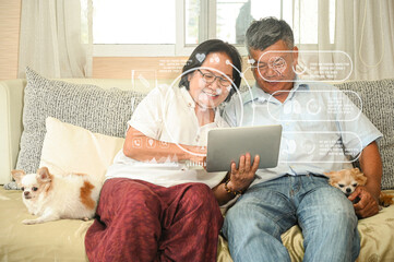 Elderly couple sitting on sofa using tablet watching hologram online health check, with two dogs sitting on sofa in living room, health and technology concept.