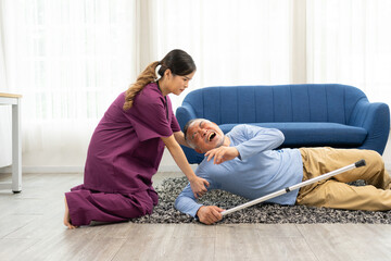 Asian caregiver helping senior male from falling on the ground and crying in pain. Elderly older...