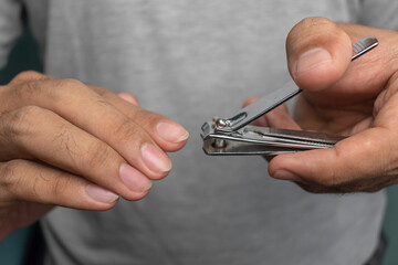 close up of man hand cutting nails using stainless steel nail cutter