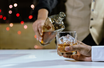 The bartender serves whiskey to customers at a bar or restaurant.