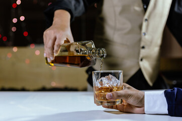 The bartender serves whiskey to customers at a bar or restaurant.