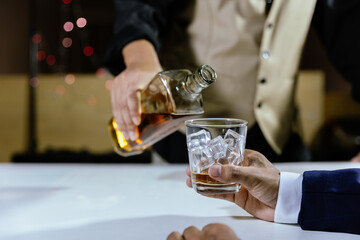 The bartender serves whiskey to customers at a bar or restaurant.