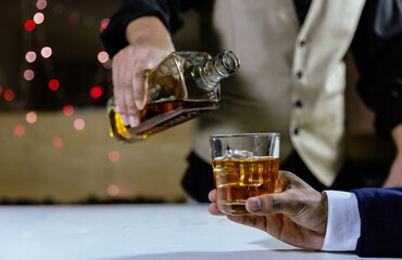 The bartender serves whiskey to customers at a bar or restaurant.