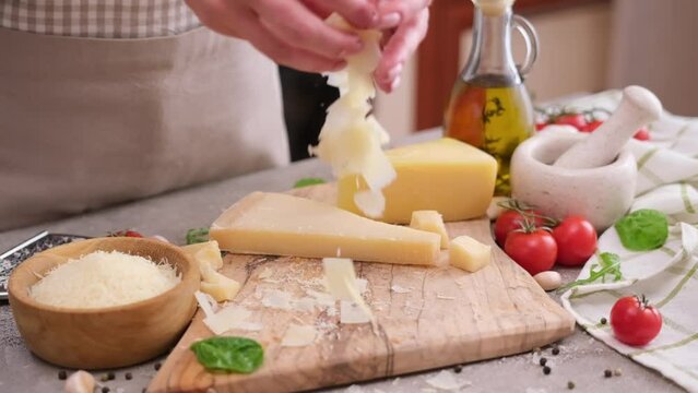woman pours sliced flakes of parmesan hard cheese on a wooden cutting board