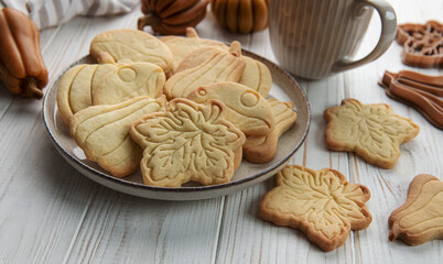 Cookies shaped like pumpkin and leaves on rustic wood background