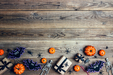 Halloween border with gifts, pumpkins, spiders, skeletons and bats on the old wooden boards.