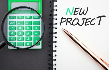 NEW PROJECT inscription on notepad. The concept of development and development of a new project, calculation of the cost of costs, investments and profitable payback of a business project.