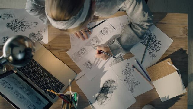 Young woman working on a storyboard in a design studio. A laptop and stationary jar on the table. Woman drawing sketches as a roadmap for the video.