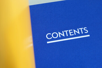 The word 'Contents' printed on the first pages of an annual report listing chapters and sections of the book. A book opened to the table of content page. Closeup macro view.