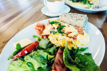 Omelet cooked with tomatoes and chives prepared with fresh lettuce as side dishes for a healthy vegetarian breakfast ready to be served