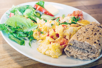 Omelet cooked with tomatoes and chives prepared with fresh lettuce as side dishes for a healthy vegetarian breakfast ready to be served