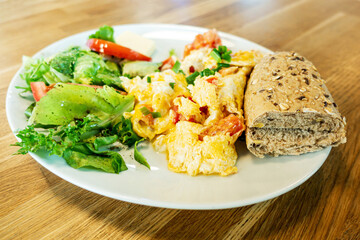 Omelet cooked with tomatoes and chives prepared with fresh lettuce as side dishes for a healthy vegetarian breakfast ready to be served