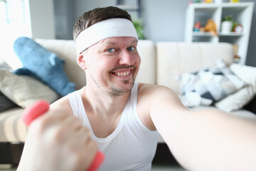 Young handsome muscular athletic young man taking selfie photo lifting dumbbells